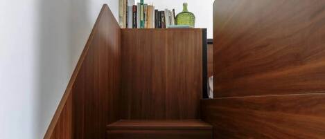 A wooden staircase with a bookshelf at the top.