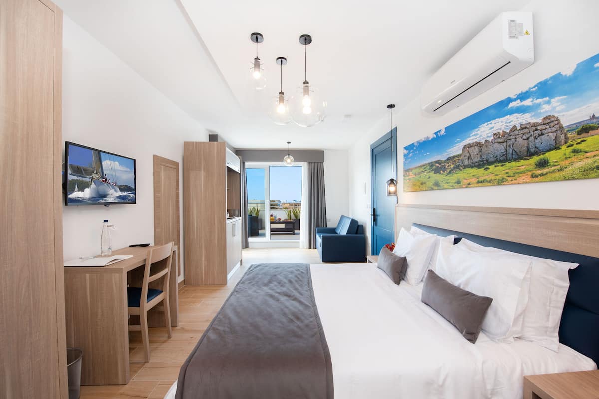 Habitación de hotel moderna con una cama grande, un escritorio, un televisor y vistas al exterior.