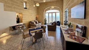 A spacious living area with a stone wall, a large arched window, and a chessboard on the table. - Georges Boutique Living (Xaghra)