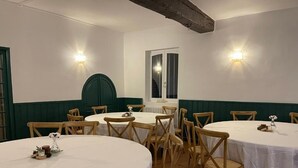 Un comedor con mesas redondas y sillas de madera, manteles blancos y lámparas fijadas a la pared.