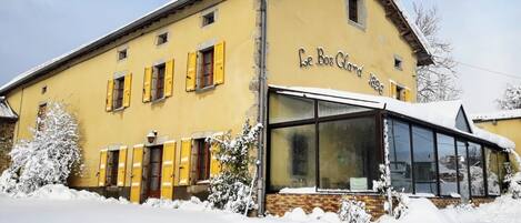 A yellow building with the sign "Le Bos Clard 1896" and a large glass window.