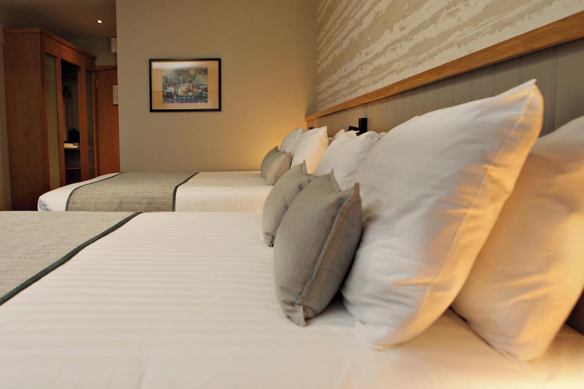 A hotel room with two beds, a wardrobe, and a framed picture on the wall.