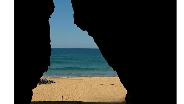 A beach view through a cave-like opening. - Beach Hotel (Downings)