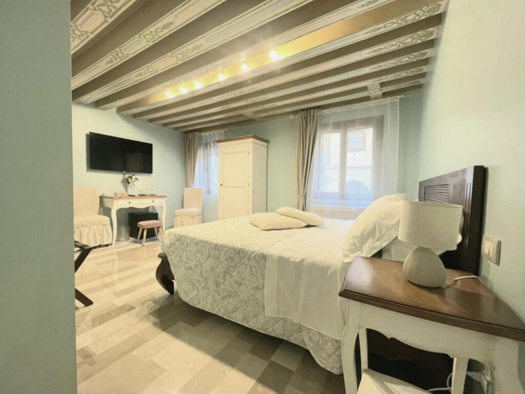 A bedroom with a bed, a desk, a chair, a TV, and a wardrobe.