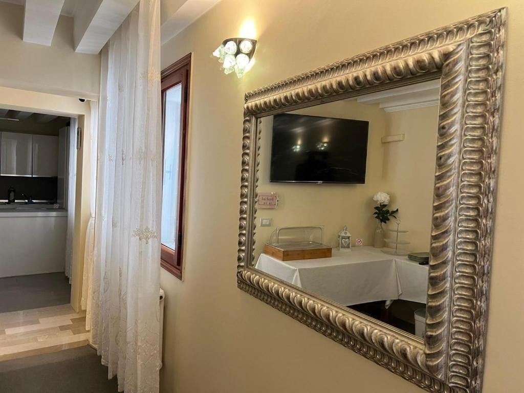 Une pièce dotée d’un grand miroir décoratif, d’un téléviseur à écran plat et d’une table recouverte d’une nappe blanche.