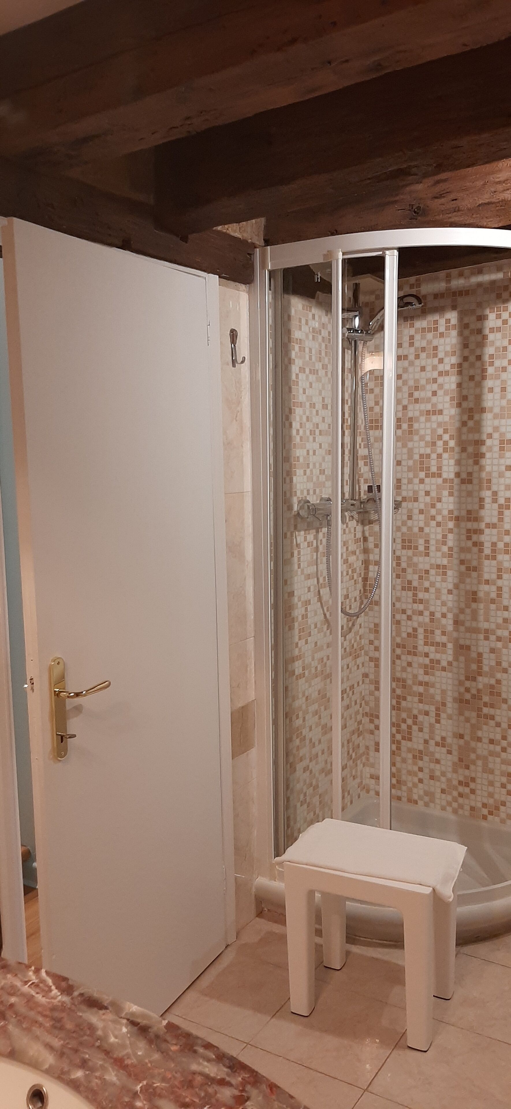 Un bagno con doccia, una panca e una porta.