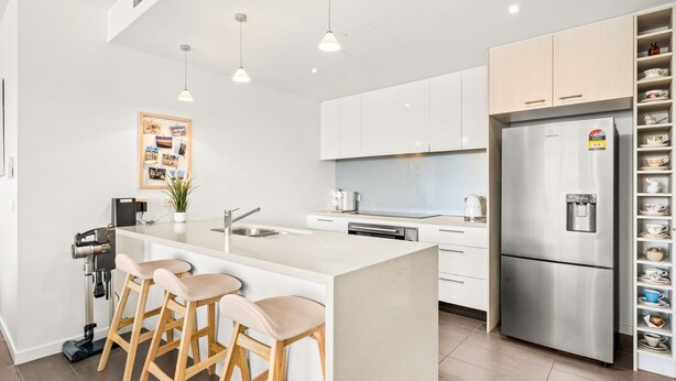 A modern kitchen with a central island, stainless steel refrigerator, and a built-in water dispenser.
