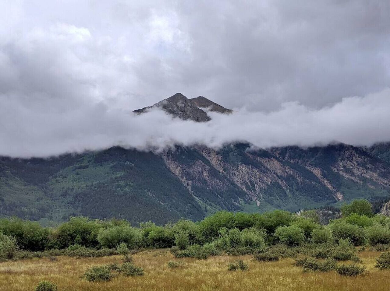 A mountain landscape with a prominent peak partially obscured by clouds.
