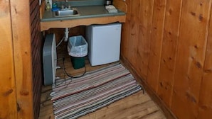 A compact kitchen with wooden walls, a built-in microwave, a sink, and a small refrigerator. - Stay Twin Lakes Cabin 3 (Twin Lakes)