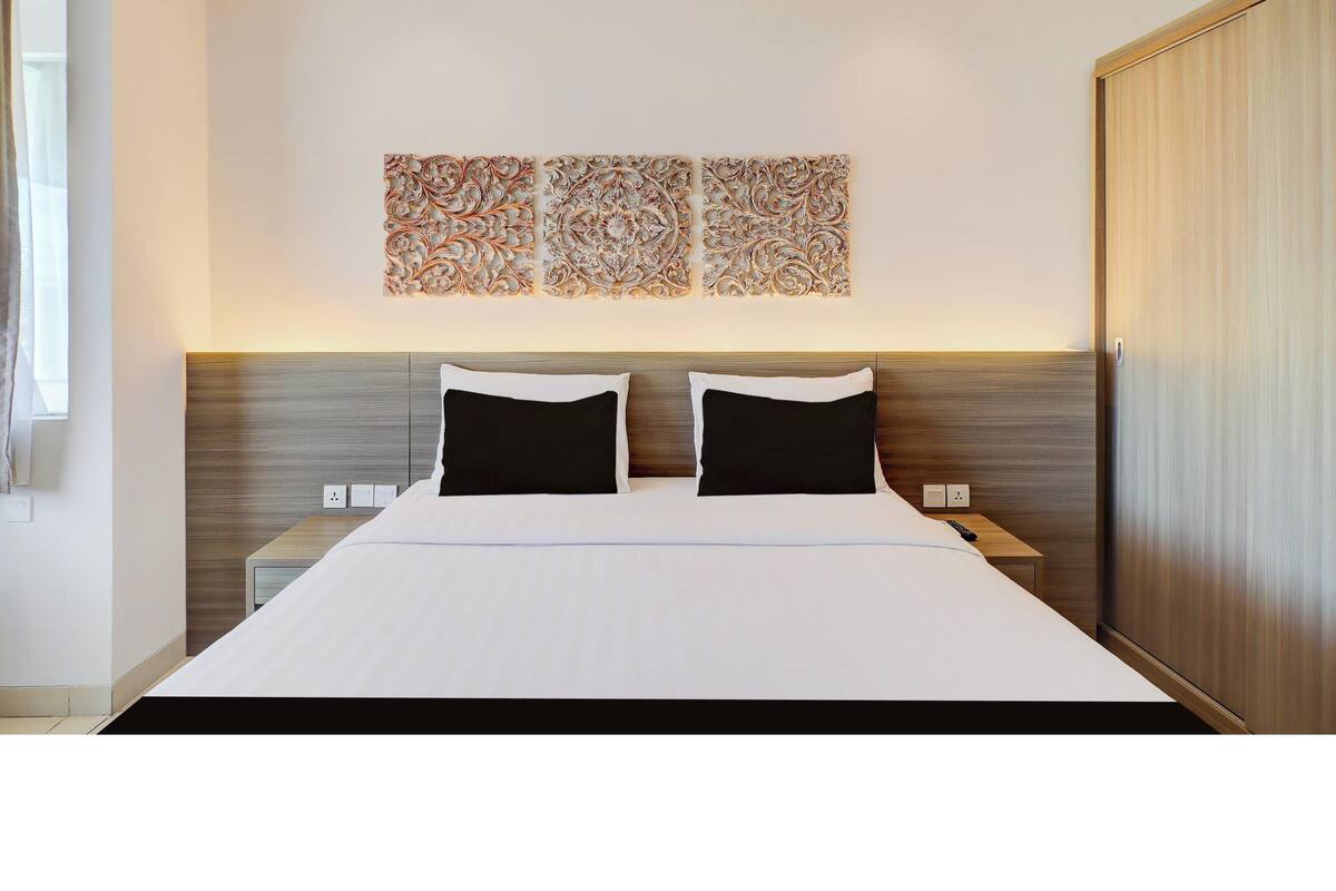 Une chambre d’hôtel moderne avec un grand lit, deux tables de chevet et une armoire.