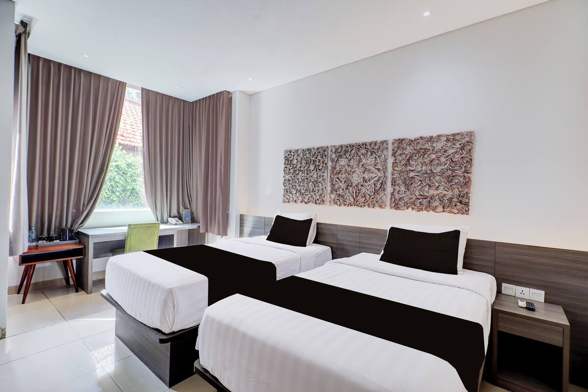 Une chambre d’hôtel avec deux lits, un bureau et une chaise.