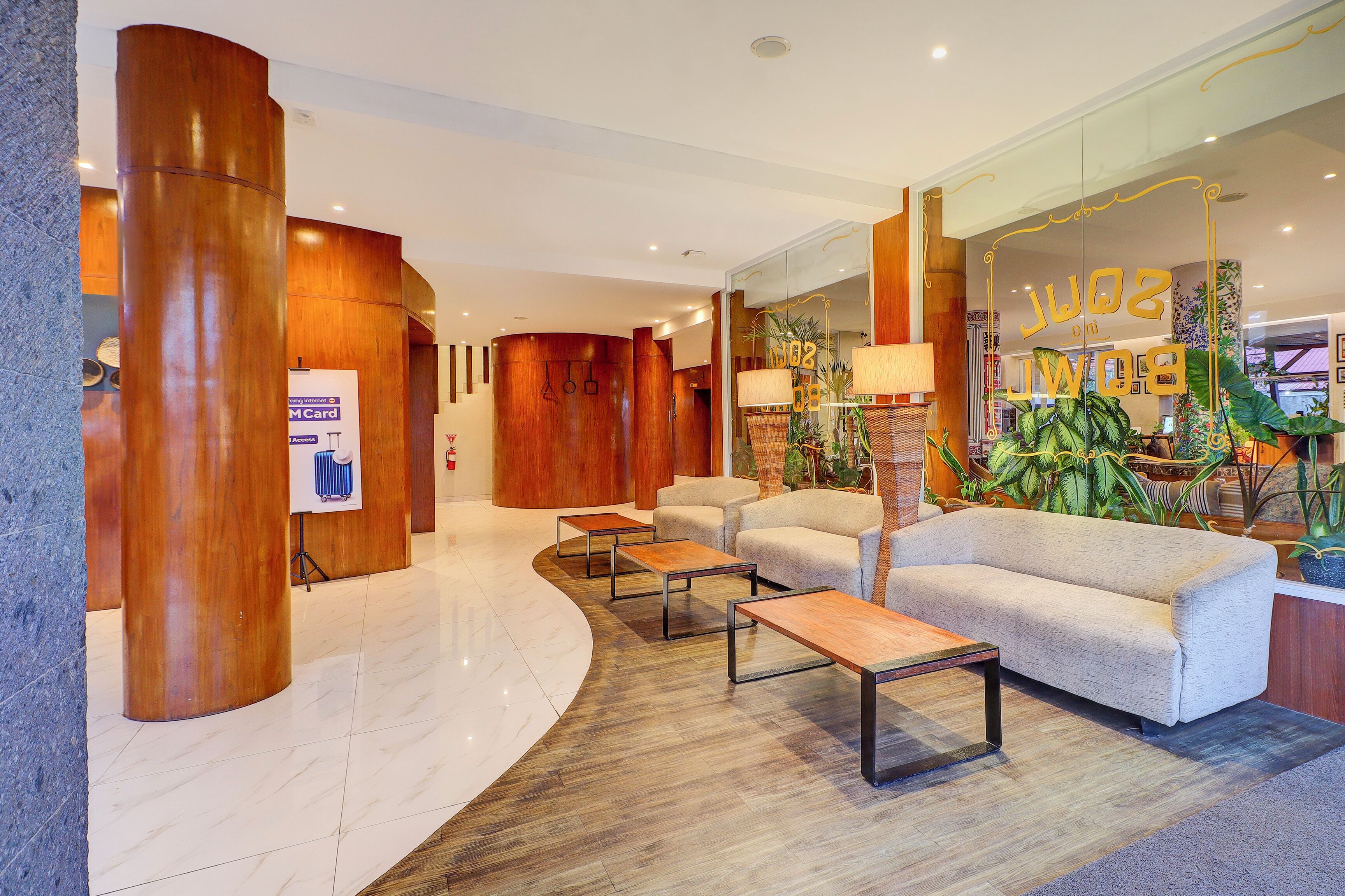 A modern lobby with a curved reception desk, seating area with sofas and tables, and a large glass wall with decorative elements.
