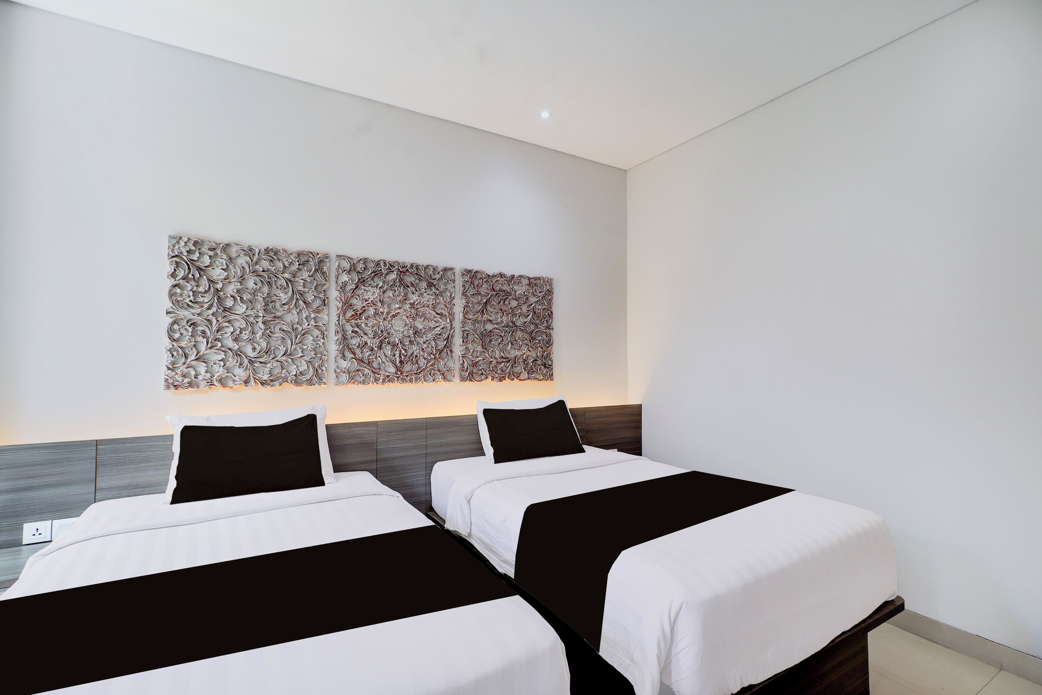 Habitación de hotel con dos camas, un cabecero moderno y un adorno decorativo sobre las camas.