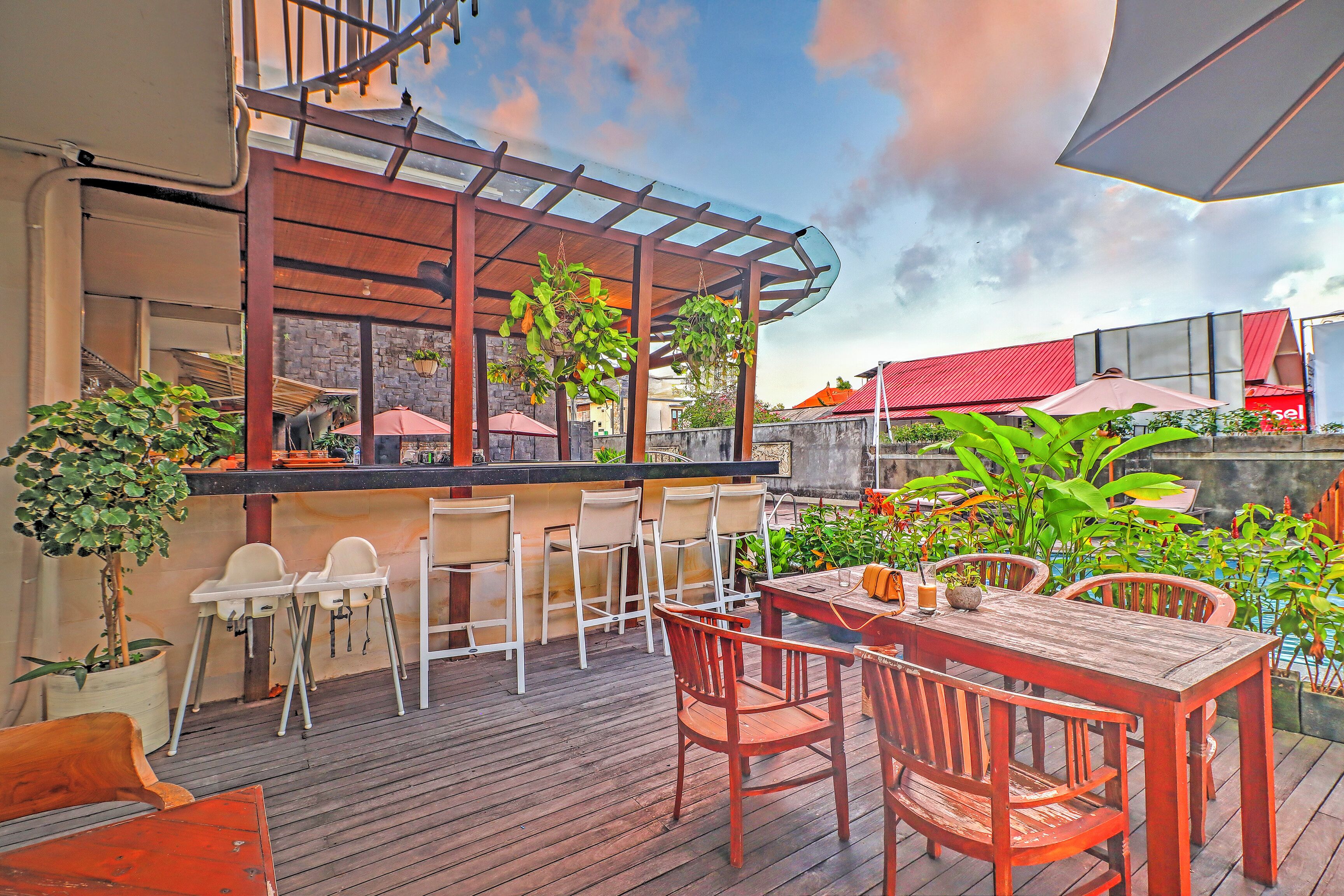 An outdoor patio with wooden furniture, a bar area, and potted plants.