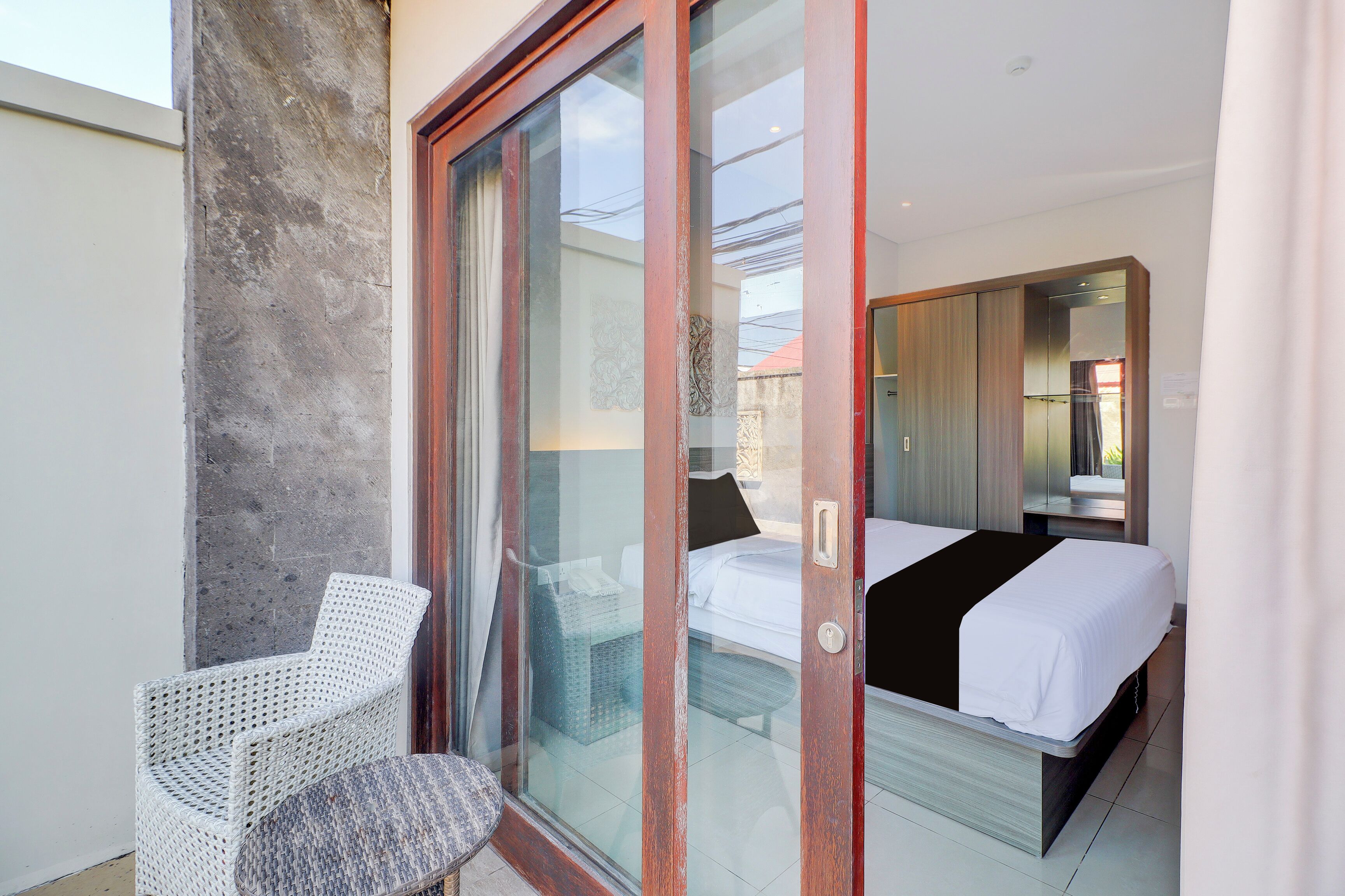 A bedroom with a bed, a chair, and a sliding glass door leading to a balcony.