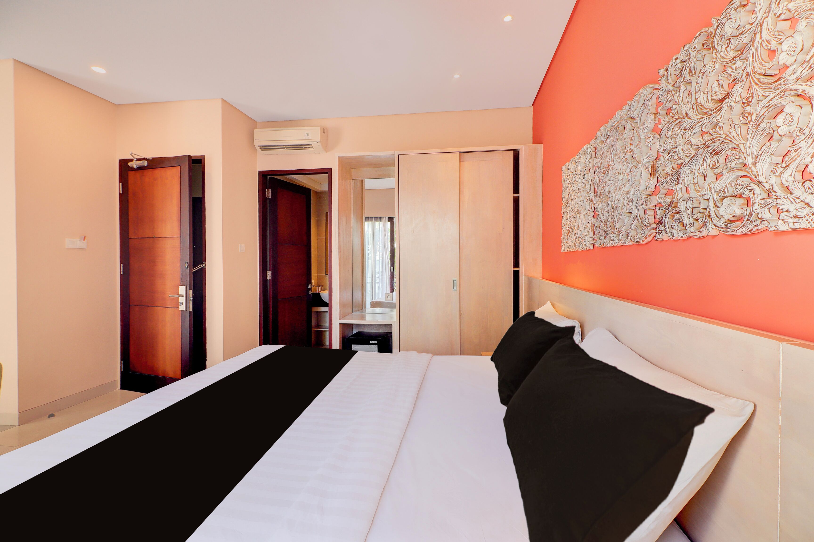 Habitación de hotel con cama, armario y baño visible a través de una puerta abierta.