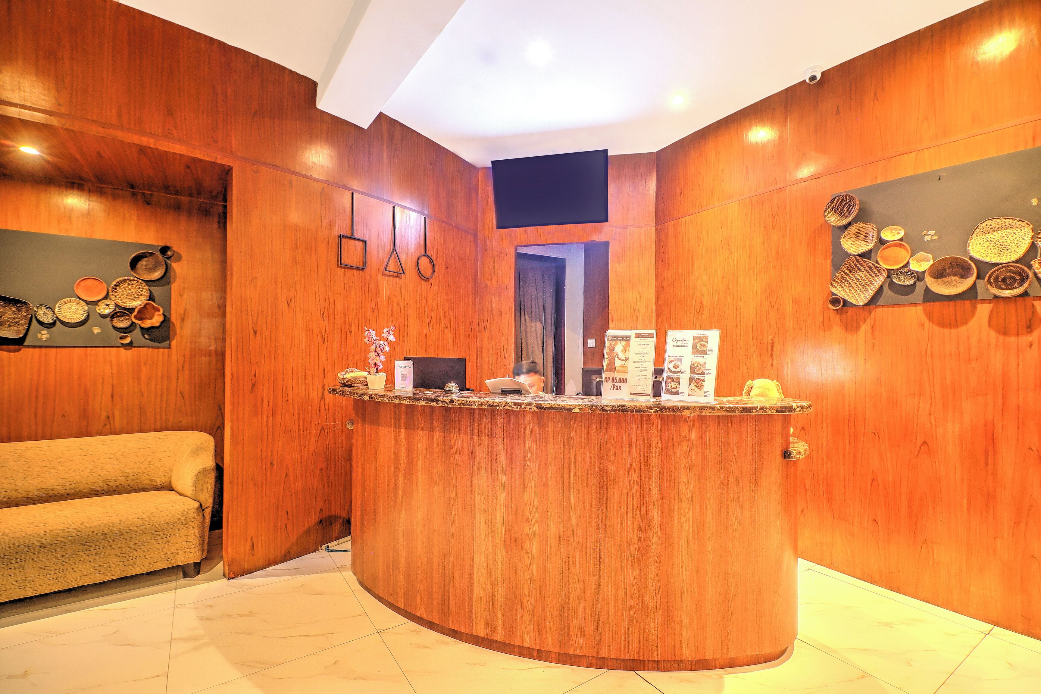Zona de recepción con mostrador de madera, un sofá y adornos en la pared.