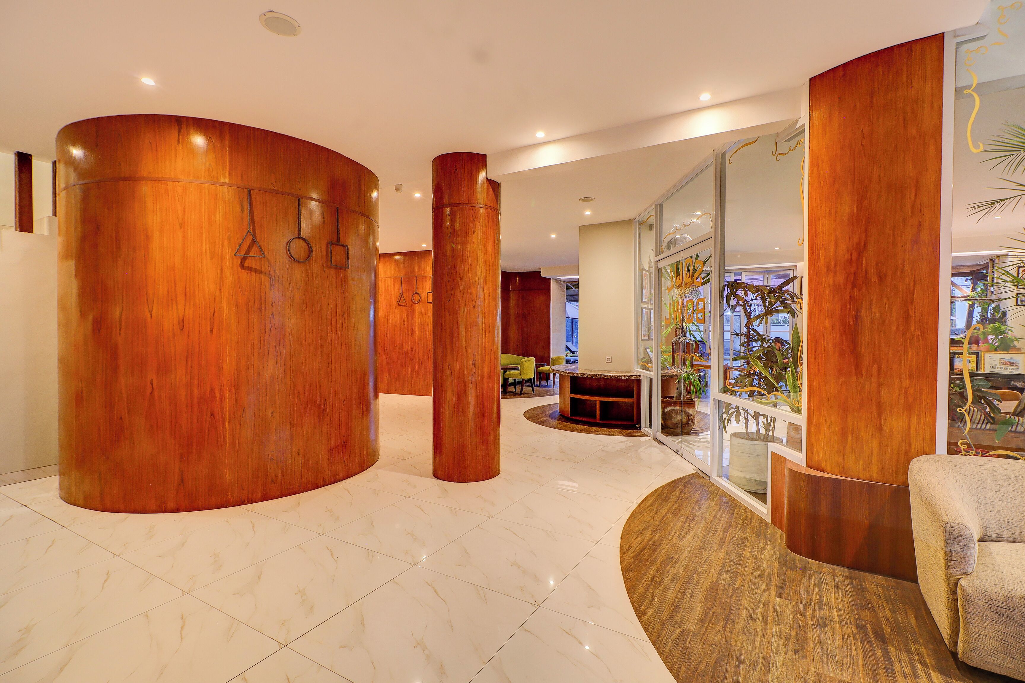 Un hall d’entrée moderne avec des colonnes en bois, un comptoir d’accueil et un espace salon.