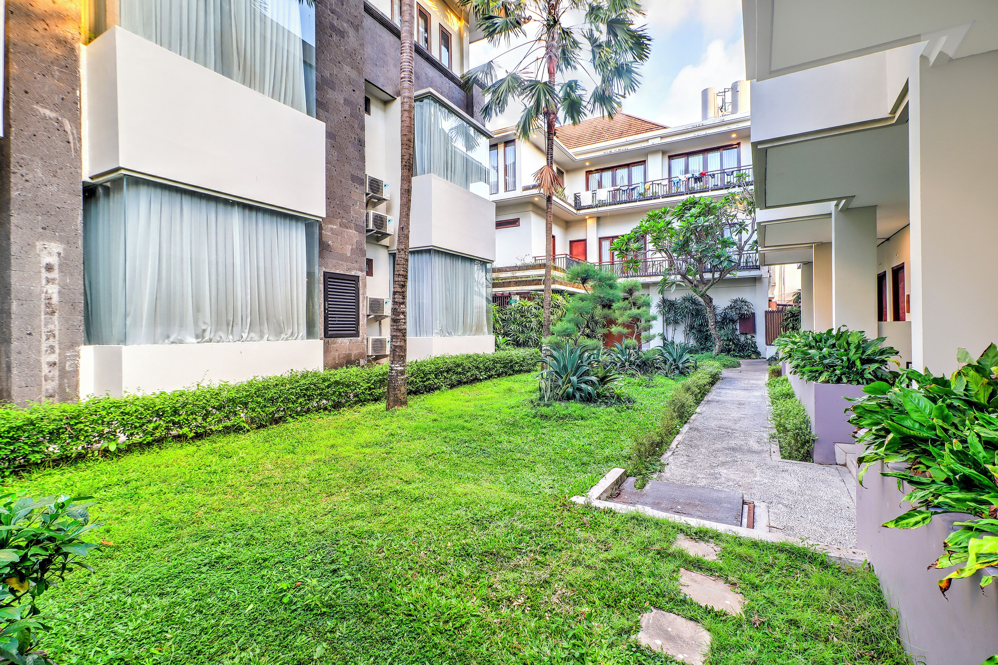 A courtyard with a well-maintained lawn, a pathway, and a variety of plants.