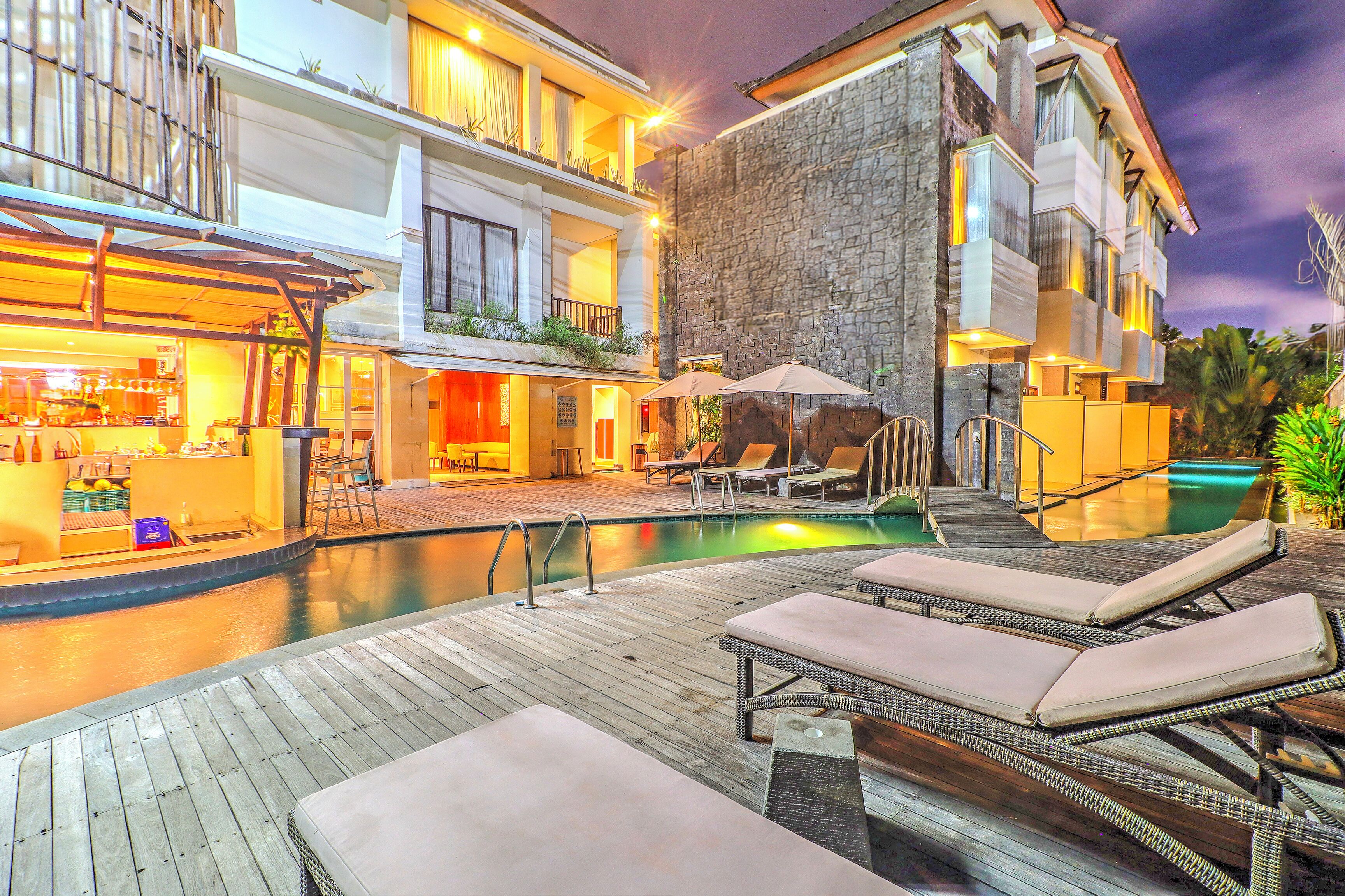 Um hotel com área de piscina, espreguiçadeiras e um bar.