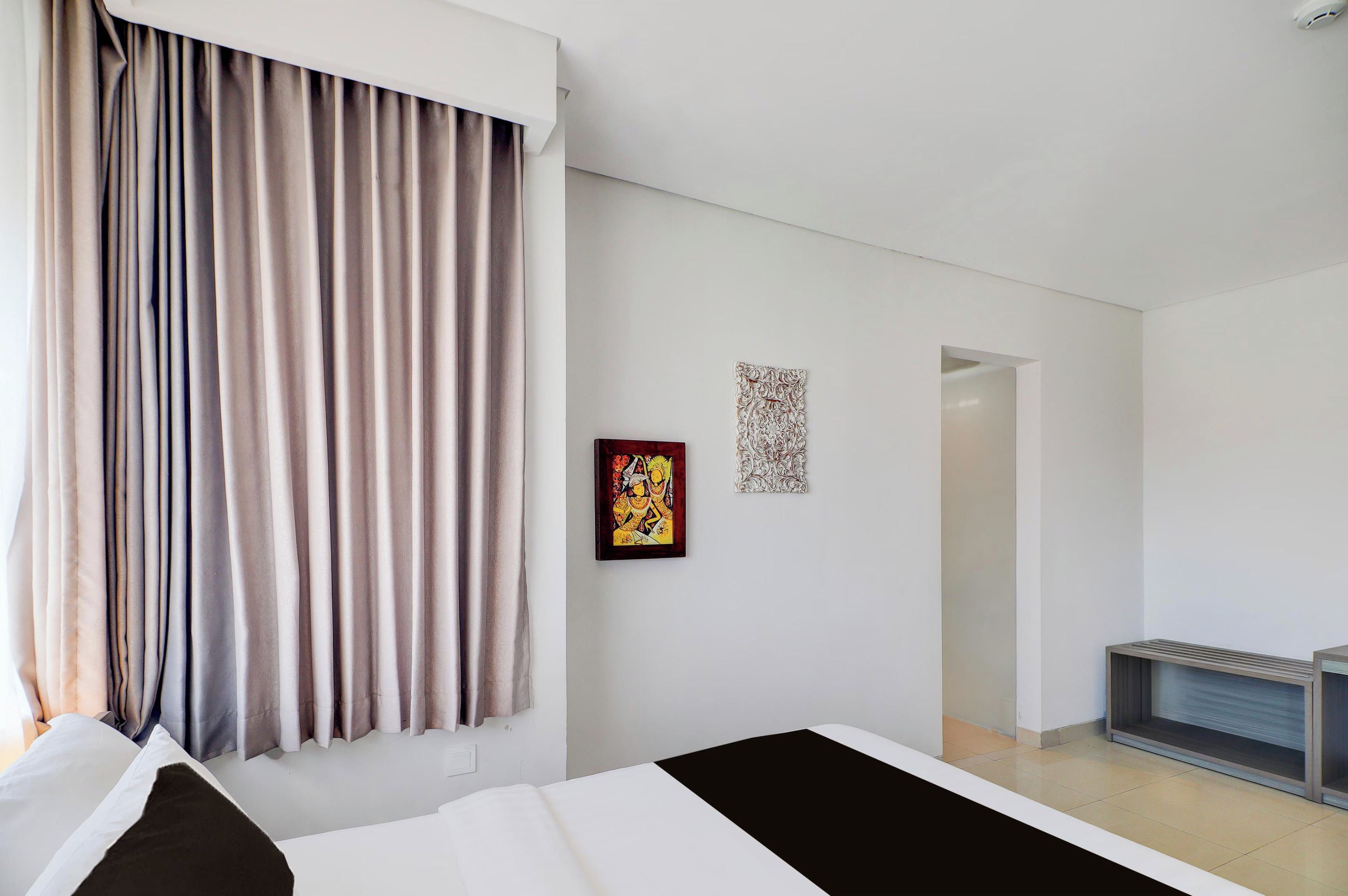A modern hotel room with a large window, a bed, a small table, and a TV stand.