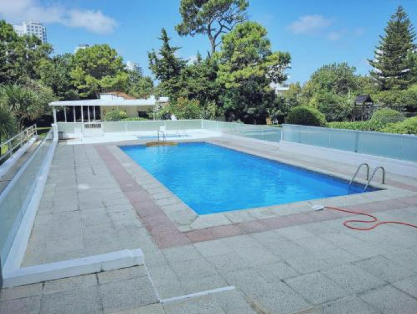 Ein rechteckiger Swimmingpool mit glasklarer blauer Wasseroberfläche, umgeben von einer gefliesten Liegefläche.