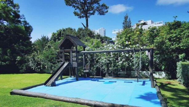 A playground with a swing set and slide, surrounded by grass and trees.