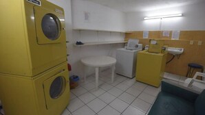 A laundry room with yellow washing machines, a small table, and a sink.
