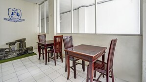 A dining area with a table and chairs, a stone fountain, and a logo on the wall. - OYO 91035 De Ritz Residence (Surabaya)