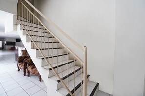 A staircase with a wooden handrail and black steps, leading to an upper floor. - OYO 91035 De Ritz Residence (Surabaya)