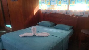 Una habitación con una cama, dos almohadas y una toalla doblada con forma de cisnes.