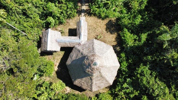 Una estructura de piedra con un pilar central y una parte superior en forma de cúpula, rodeada de abundante follaje verde.