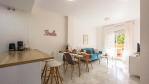 A modern living space with a dining area, a sofa, and a kitchen counter.
