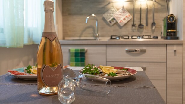 Une cuisine avec une bouteille de vin, des verres et des assiettes remplies de nourriture.