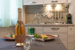 Una cocina con una botella de vino, copas y platos de comida.
