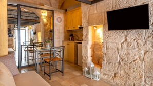 Una cocina rústica con paredes de piedra, armarios de madera y un comedor con mesa y sillas.