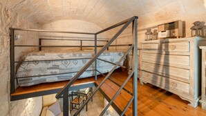 Un dormitorio con una cama litera, un aparador de madera y un techo de piedra.