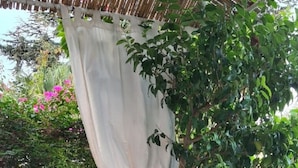 Un banc en pierre, une petite plante et un espace aménagé au bord de la piscine avec une table et des chaises.