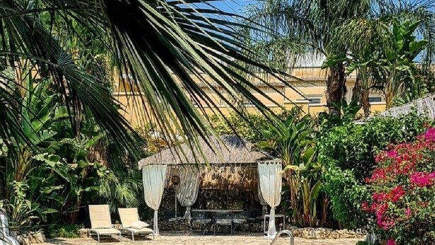 Une piscine avec des chaises longues et un kiosque.