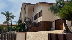 Ein modernes, zweistöckiges Haus mit Steineingang, Holztreppe und einem begrenzten Auffahrt.