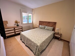 A bedroom with a bed, bedside tables, a dresser, a radiator, and a window. - Villa 'Carme' with Sea View, Wi-Fi and Air Conditioning (Calonge)