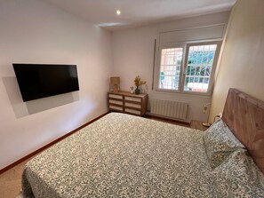 A bedroom with a bed, a dresser, a TV mounted on the wall, and a window with a view. - Villa 'Carme' with Sea View, Wi-Fi and Air Conditioning (Calonge)