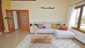 Ein Wohnzimmer mit einer Couch, einem Holztisch und einem Fenster mit Vorhängen.