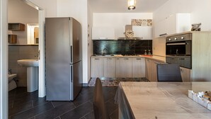 A modern kitchen with a refrigerator, sink, stove, and dining area. - Holiday Home "Open Space Nel Sulcis" with Private Garden & A/C (Masainas)