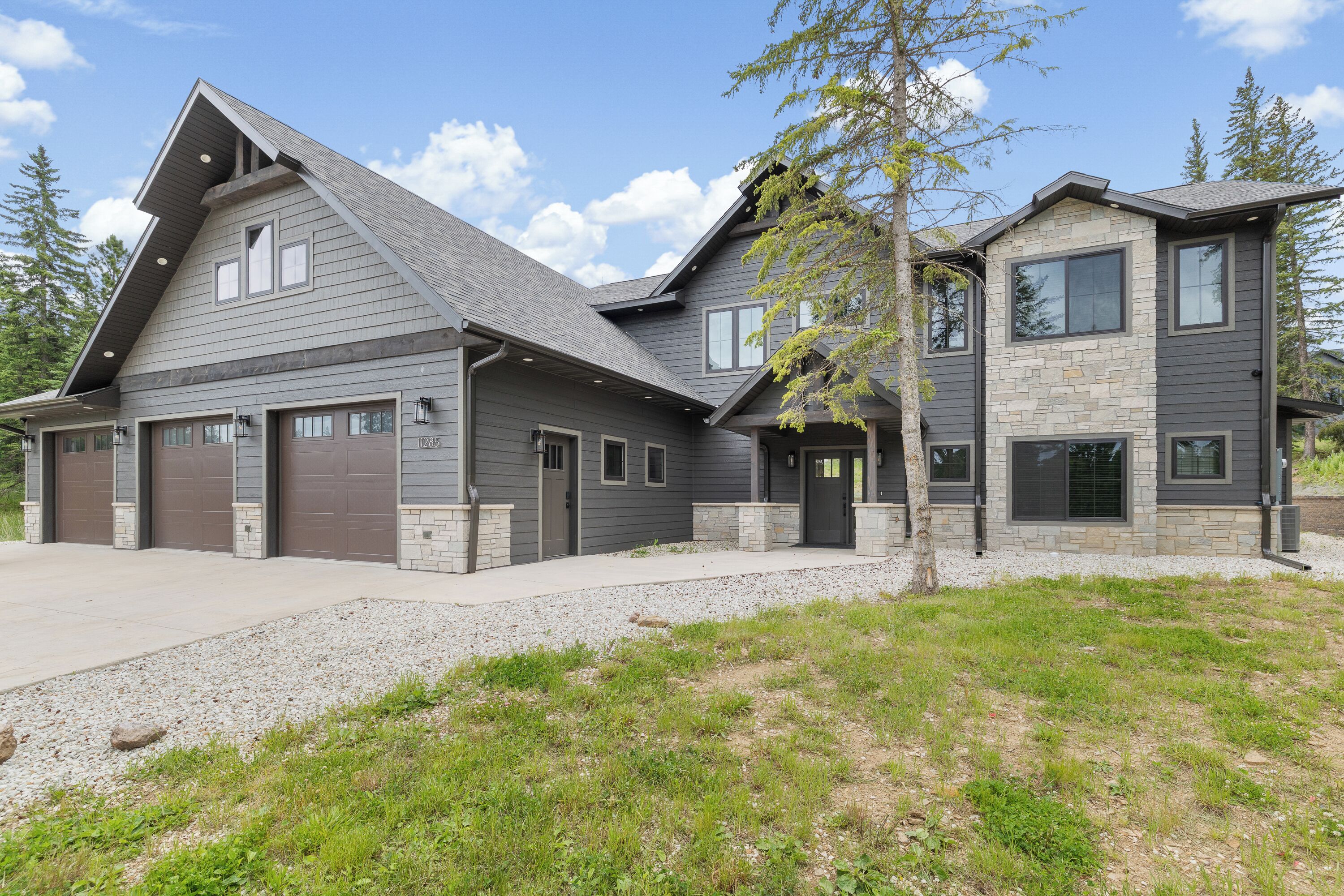 Ein zweistöckiges Haus mit Garage, Naturstein-Fassade und geneigtem Dach.