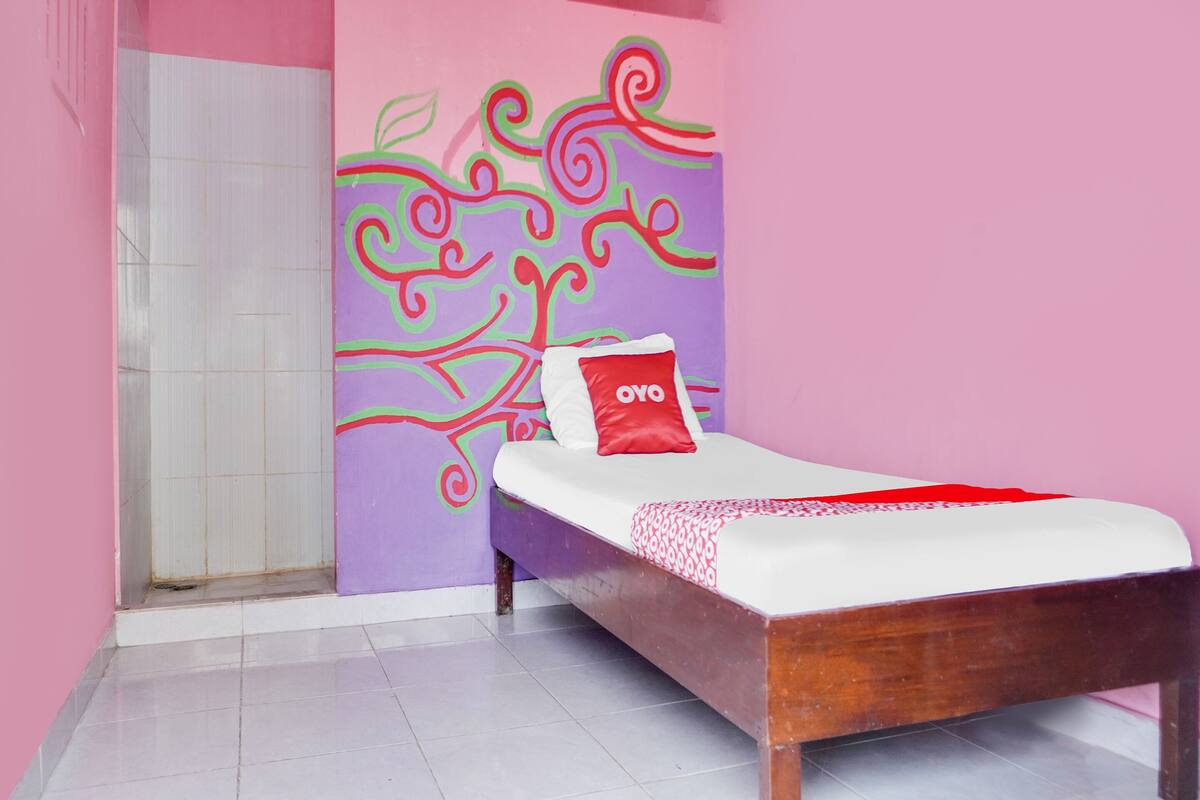 Un dormitorio con cama, ducha y un diseño de árbol en la pared.