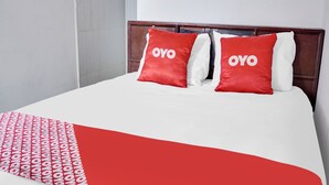 Un lit avec deux oreillers rouges et un couvre-lit blanc orné d’un motif rouge.
