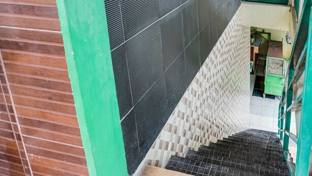 Un escalier avec des carreaux noirs et beiges, des rampes vertes et un plancher en bois.