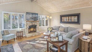 A spacious living room with a fireplace, large windows, and a cozy seating area. - 3875 The Hideout - Quiet Area, Walk to Town (Carmel-by-the-Sea)