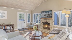 A spacious living room with a fireplace, large windows, and a cozy seating area. - 3875 The Hideout - Quiet Area, Walk to Town (Carmel-by-the-Sea)